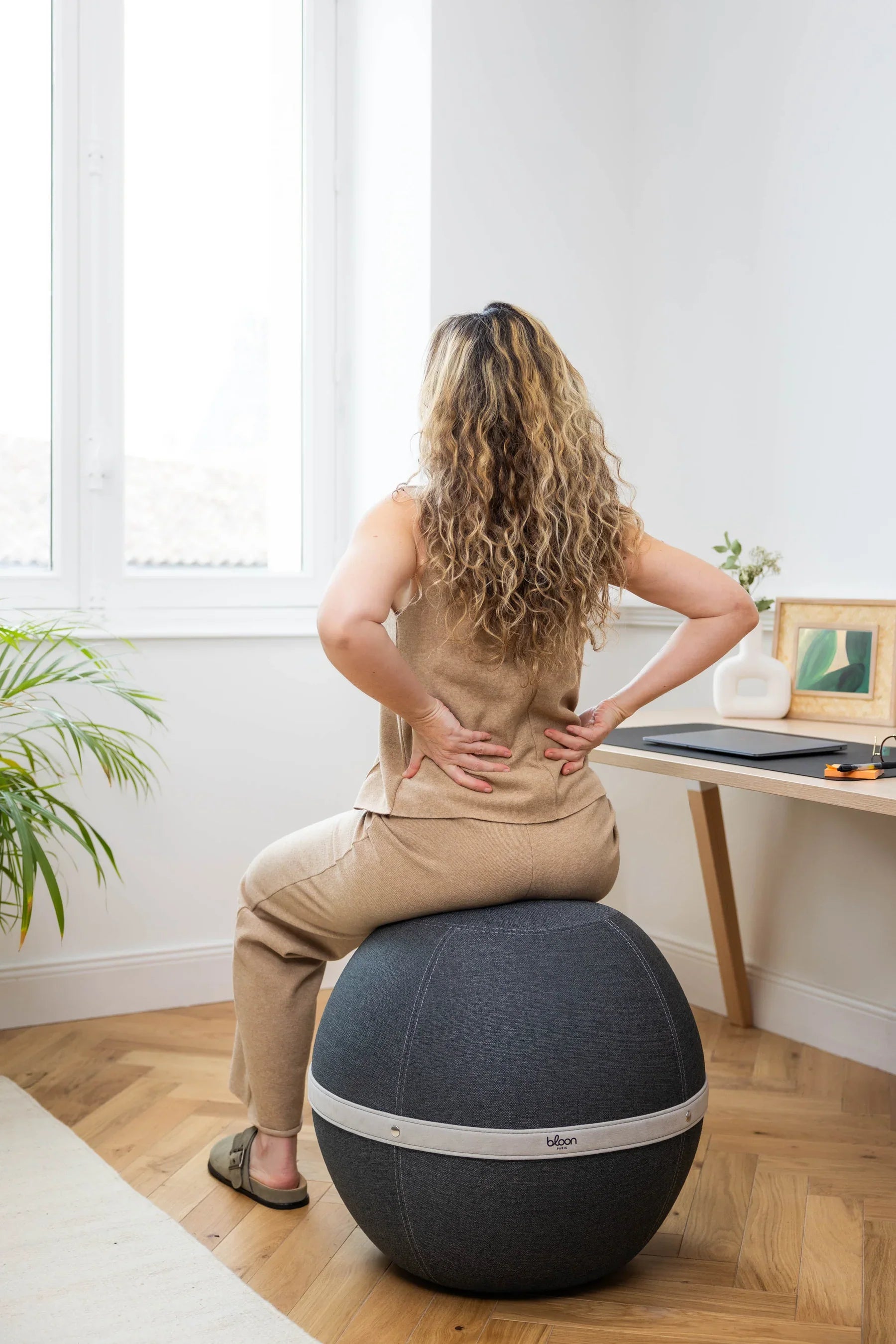 How to know if a back pain is serious ? Woman sitting on a Bloon seat doing some back stretches