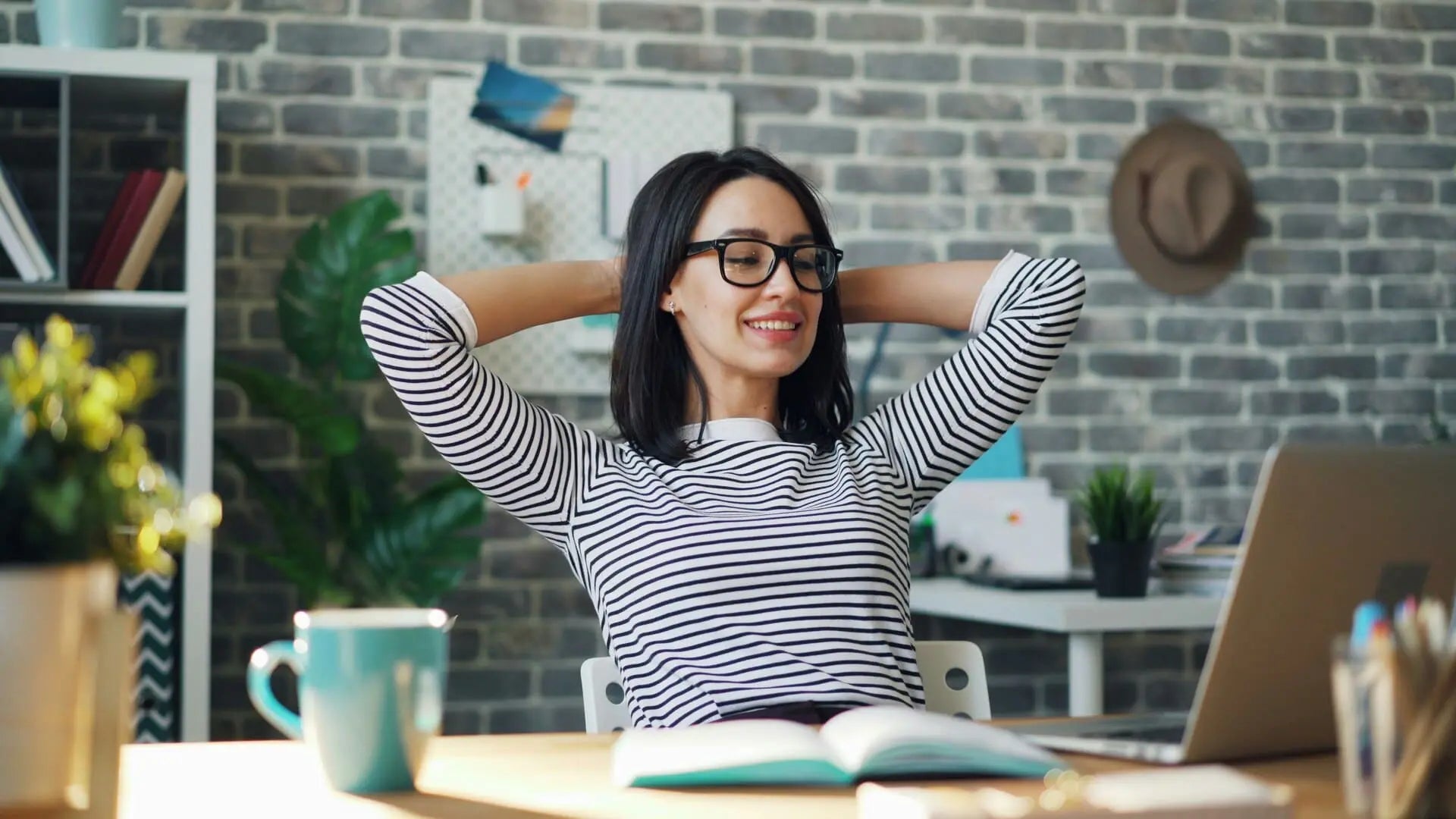 Staying fit at the office: a woman sitting at her desk looking relaxed, happy and healthy.