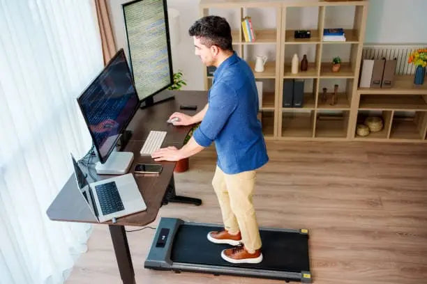 walking while working : man on a treadmill facing his desk and computer